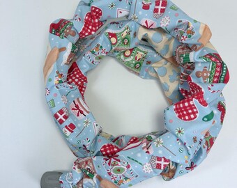 Può includere: Un oggetto circolare rivestito in tessuto, con sfondo azzurro e motivo natalizio ripetuto. Il motivo include omini di pan di zenzero, regali confezionati, fiocchi di neve ed elementi a scacchi rossi e bianchi. L'oggetto ha un'estremità cilindrica grigia.