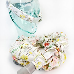 May include: A white fabric cover with a floral pattern for a CPAP hose. The cover is made of soft, breathable fabric and features a variety of colorful flowers and leaves. The cover is designed to fit snugly around the hose and help to keep it clean and free of dust and debris.