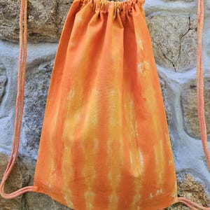 May include: Orange and yellow tie-dye drawstring bag with white cotton drawstrings.
