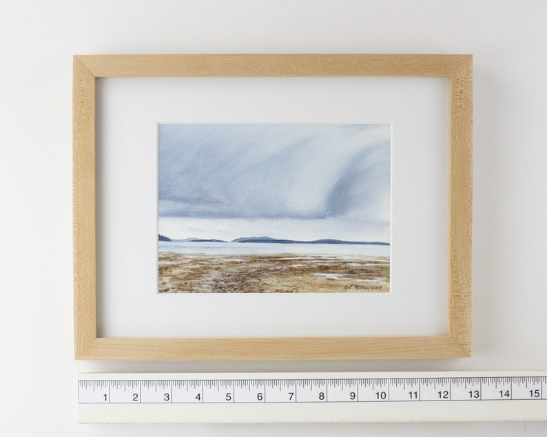 May include: A framed watercolor painting of a seascape with a cloudy sky and a distant shoreline. The painting is in a light wood frame.