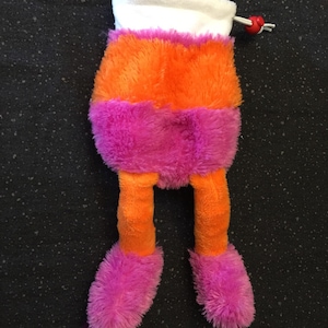 May include: A plush toy with orange and pink fur. The toy has a white top and long legs. The toy has a red button on the top.