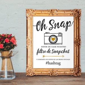 Może przedstawiać: Biały znak z czarnym tekstem i złotą grafiką aparatu. Tekst brzmi "Oh Snap" i "Favor de usar nuestro filtro de Snapchat" oraz "Y comparta sus fotos en las redes sociales #hashtag".
