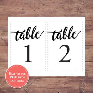 May include: Two white table number cards with black text. The first card says "table 1" and the second card says "table 2".