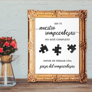 Op de afbeelding: Een wit bord in een gouden lijst met zwarte tekst die "Sin ti nuestro rompecabezas no está completo." luidt. Het bord heeft ook drie zwarte puzzelstukjes en de tekst "Favor de firmar una pieza del rompecabezas."