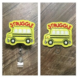 May include: A yellow school bus with black stripes and the word "STRUGGLE" in red letters. The bus is attached to a retractable badge holder.