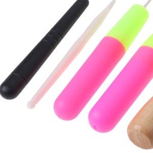 May include: A set of five tools for crafting, including a black plastic tool, a white plastic tool, two pink and yellow plastic tools, and a wooden tool.