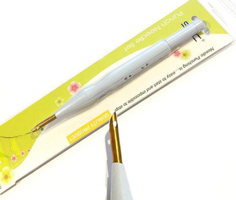 May include: A white punch needle with a gold tip and a yellow and white label that reads "Punch Needle Set" and "Needle Punching is...easy to start and impossible to stop QUALITY PRODUCT".