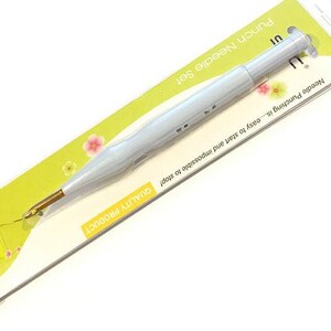 May include: A white punch needle with a gold tip, packaged on a yellow and green background. The packaging reads "Punch Needle Set" and "Needle Punching is...easy to start and impossible to stop! QUALITY PRODUCT".