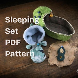 Puede incluir: Un juego para dormir hecho a mano, que incluye una cuna verde, una prenda con capucha y una estera en forma de hoja. La cuna es verde con detalles florales azules y un interior gris. La prenda con capucha es azul claro y verde. El texto "Sleeping Set PDF Pattern" es visible.