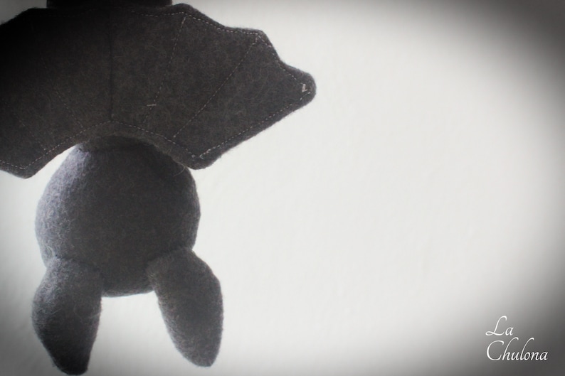Puede incluir: Un juguete de peluche de murci&eacute;lago negro con una textura suave y peluda. El murci&eacute;lago est&aacute; colgado boca abajo con las alas extendidas.