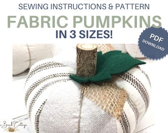 May include: A fabric pumpkin sewing pattern with text reading SEWING INSTRUCTIONS & PATTERN FABRIC PUMPKINS IN 3 SIZES! PDF DOWNLOAD. The pumpkin is made of white and brown striped fabric with a natural wood stem and a dark green felt leaf.