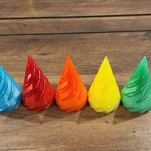 May include: Five colorful, cone-shaped, 3D printed objects. The cones are arranged in a row from left to right: blue, red, orange, yellow, and green.