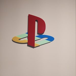 May include: A red, blue, yellow and green PlayStation logo on a white wall.