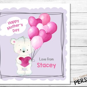 May include: A white teddy bear holding a pink heart, surrounded by pink and white heart-shaped balloons. The card reads "Happy Mother's Day" and "Love from Stacey".