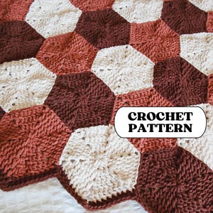 May include: A handmade crochet blanket featuring a geometric pattern of interlocking hexagons. The blanket uses a palette of warm colors, including cream, terracotta, and deep brown. The text "CROCHET PATTERN" is displayed on the blanket.