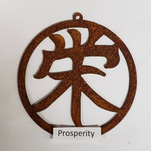 Może przedstawiać: Okrągły ornament z rdzawego metalu z wyciętym w środku chińskim znakiem oznaczającym "dobrobyt". Słowo "Prosperity" jest napisane pod okręgiem.