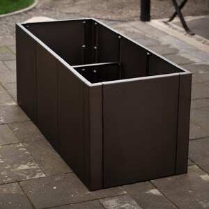 May include: A rectangular, dark brown metal planter box with a divided interior. The planter is empty and sits on a stone patio. The box is approximately 36 inches long, 18 inches wide, and 18 inches tall.