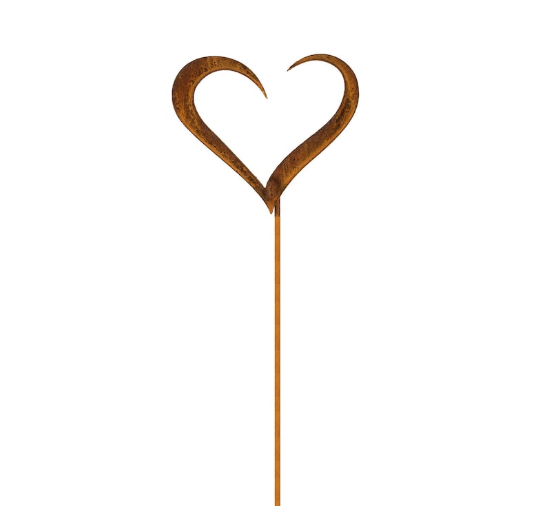 May include: A garden stake featuring a heart-shaped top with a textured, weathered brown rust finish. The heart is formed by two curved metal pieces that meet at the bottom, attached to a long, straight, thin metal rod extending downward.