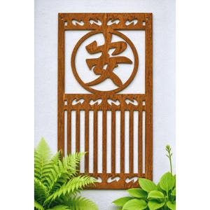 May include: A rectangular, rust-colored metal wall panel featuring a cutout design. The upper section contains a circular frame enclosing the Japanese kanji character for peace, while the lower portion consists of vertical slats and decorative borders.