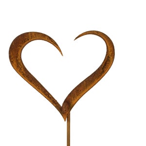 May include: A heart-shaped metal ornament featuring a textured, rusted brown finish. The heart is open at the top and is attached to a thin, straight metal rod extending downward from the bottom point of the heart shape.