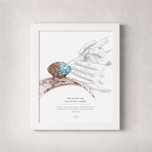 May include: Framed art print featuring a watercolor illustration of hands sculpting clay. The artwork includes the text "We are the clay, You are the sculptor" and a Bible verse. The color palette includes brown, blue, and white.