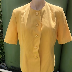 May include: A yellow short-sleeved blazer with a mandarin collar and five button closures.