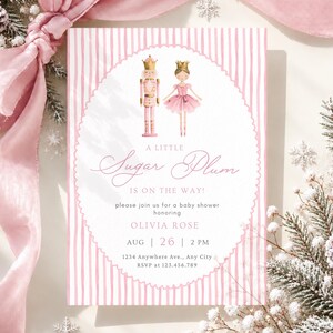 Puede incluir: Una tarjeta de invitación rectangular para baby shower con un borde de rayas verticales rosas y blancas. El centro presenta una ilustración de un cascanueces y una bailarina con el texto A LITTLE Sugar Plum IS ON THE WAY! OLIVIA ROSE AUG 26 2 PM 1234 Anywhere Ave., Any City RSVP at 123.456.789.