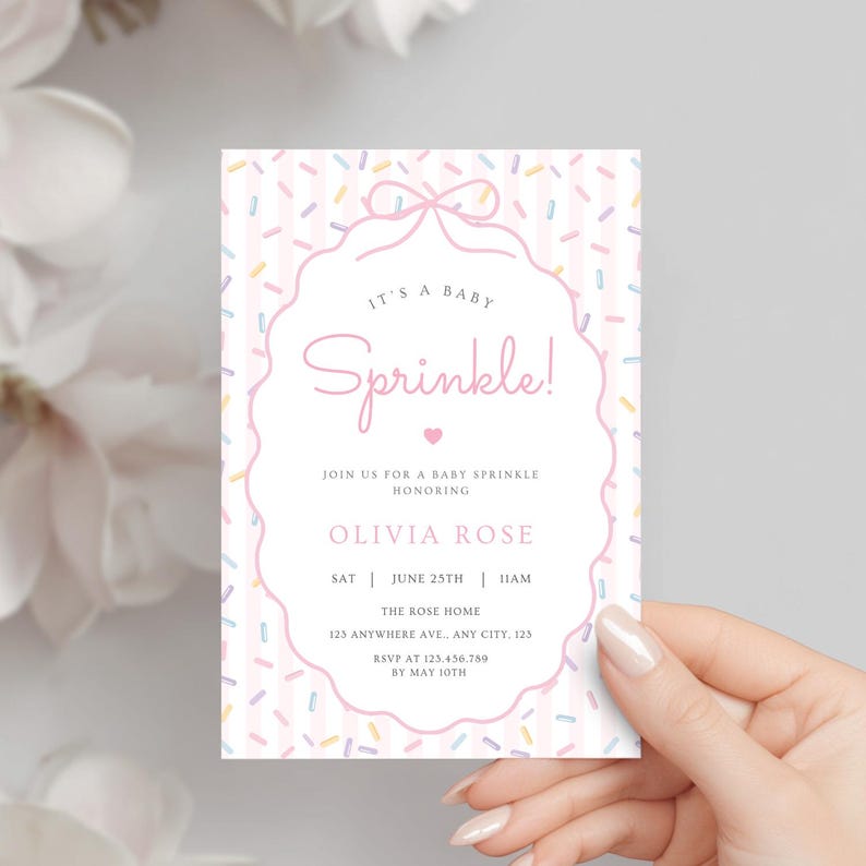 Op de afbeelding: Een baby sprinkle uitnodigingskaart met een roze en witte gestreepte achtergrond en kleurrijke confetti sprinkles. De kaart bevat de tekst "It's a Baby Sprinkle!" in een decoratief lettertype, samen met evenementdetails.