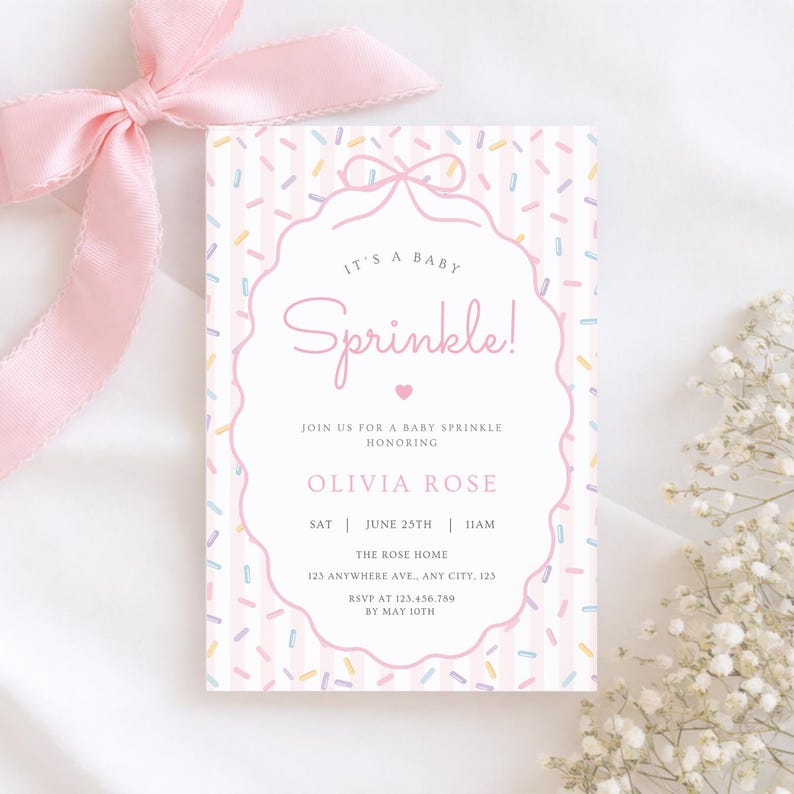 Op de afbeelding: Een baby sprinkle uitnodiging met een roze strik en lint. De uitnodiging heeft een roze en witte gestreepte achtergrond met kleurrijke hagelslag. De tekst luidt "It's a Baby Sprinkle!" en bevat evenementdetails.