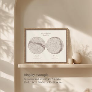 May include: Framed print with a celestial map design. The print features two circular star charts, labeled "Engaged" and "Married", with the text "Our Love Story" above. The frame is a light brown color. The print is displayed on a shelf.