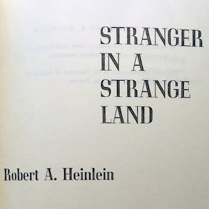May include: The cover of a paperback book titled "Stranger in a Strange Land" by Robert A. Heinlein. The book is published by G.P. Putnam's Sons in New York.
