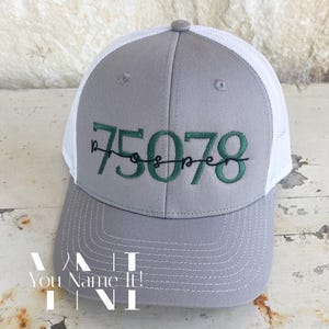 May include: Gray and white trucker hat with green embroidered text that reads "75078 prosper".