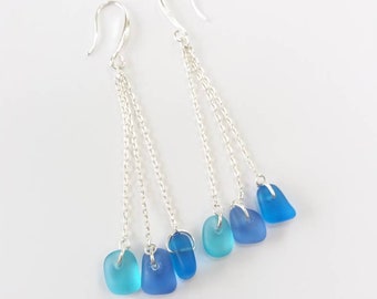 May include: Silver dangle earrings with three chains and blue glass beads. The beads are graduated in size and shade, from light blue to dark blue.