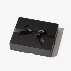 May include: A black gift box with a black satin ribbon tied in a bow.