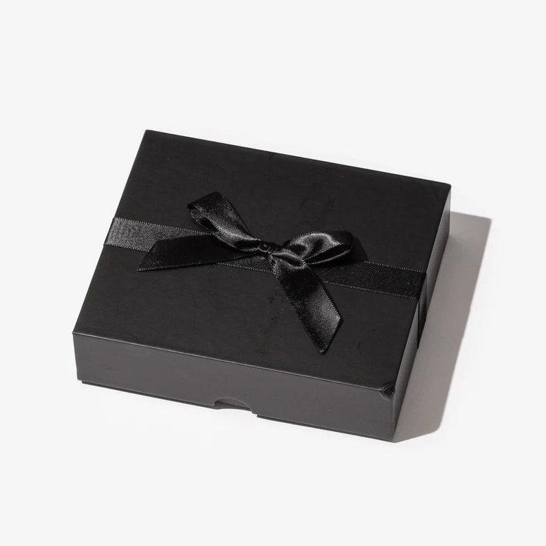 May include: A black gift box with a black satin ribbon tied in a bow.