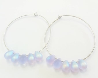 May include: Silver hoop earrings with iridescent light blue teardrop-shaped glass beads.