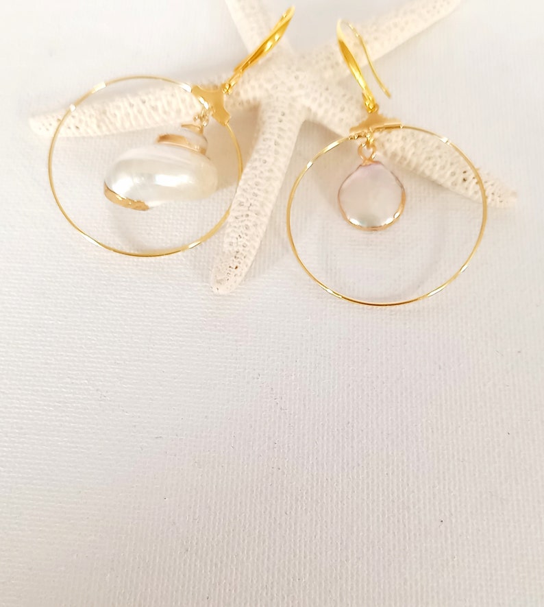 May include: A pair of gold hoop earrings with a white pearl pendant on each hoop.