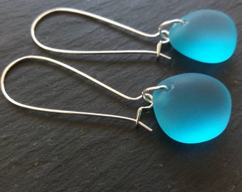 May include: A pair of silver dangle earrings with light blue glass teardrop-shaped beads.