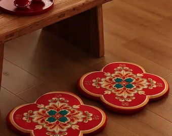 May include: Two red floor cushions with intricate gold and green embroidery. The cushions are shaped like a four-leaf clover and have a traditional Chinese design.