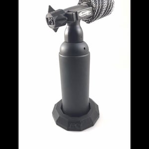 May include: A black torch with a cylindrical body and a faceted base. The torch head has a star-shaped nozzle and the letters "PS" are visible on the base. The torch is designed for precision work.