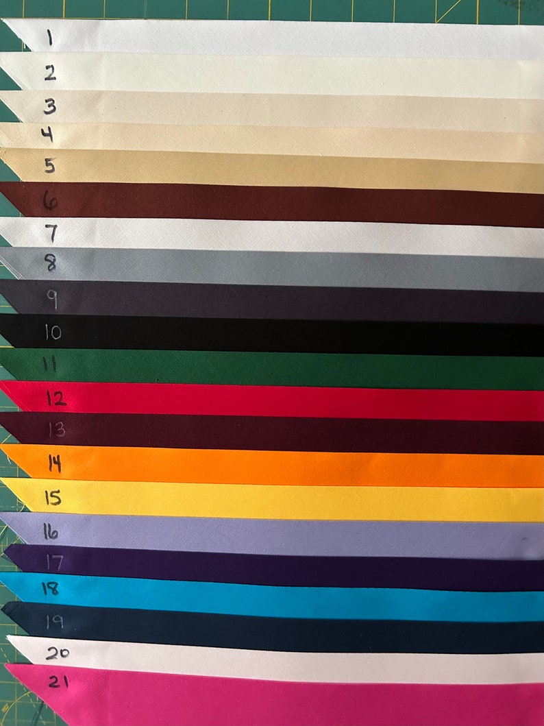 Op de afbeelding: Eenentwintig stofstalen in verschillende kleuren, genummerd van 1 tot en met 21. De stalen zijn verticaal gerangschikt, met de nummers links van elk staal.