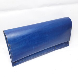 May include: A blue leather wallet with a stitched seam.