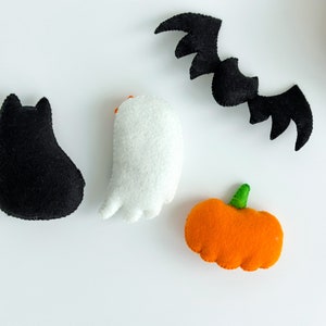 May include: A set of felt Halloween decorations including a black cat, a white ghost, an orange pumpkin, and a black bat.