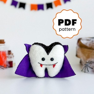 May include: PDF pattern for a felt vampire tooth plush toy. The tooth is white with a black cape and red fangs. The toy has a cute, smiling face.