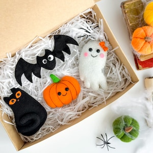 May include: A set of five felt Halloween decorations in a box. The decorations include a black cat, a bat, a ghost, a pumpkin, and a green pumpkin.