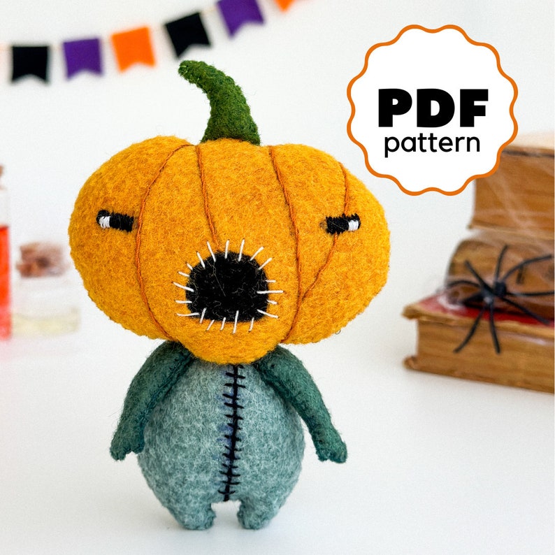 May include: A felt pumpkin character with a stitched mouth and googly eyes. The pumpkin is orange and the body is green. The character is standing on a white surface. PDF pattern.