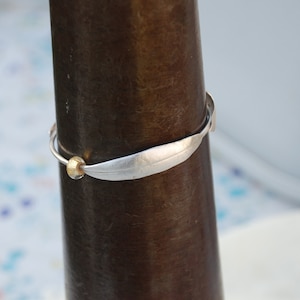 May include: A silver bracelet with a leaf-shaped design and a gold bead accent.