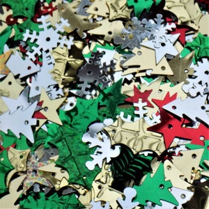 May include: Assortment of Christmas-themed metallic sequins in gold, silver, red, and green. The sequins are shaped like stars, snowflakes, Christmas trees, and holly leaves.
