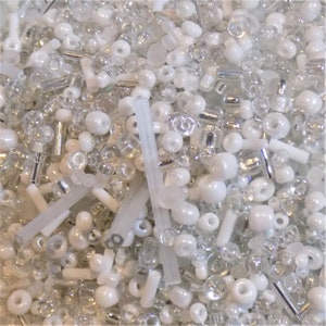 May include: A mix of white and clear glass beads and silver-coloured beads. The beads are of various shapes and sizes.