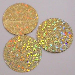 May include: Three round iridescent gold sequins with a hole in the centre. The sequins have a speckled pattern.